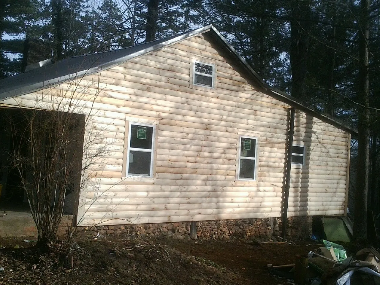 New log siding and dark metal roofing on a gable end in Cannonville