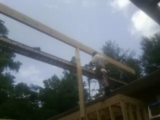 Carpenter setting a ridge beam over a new addition frame — Ice Dam Removal by Roofing Brothers in Cannonville