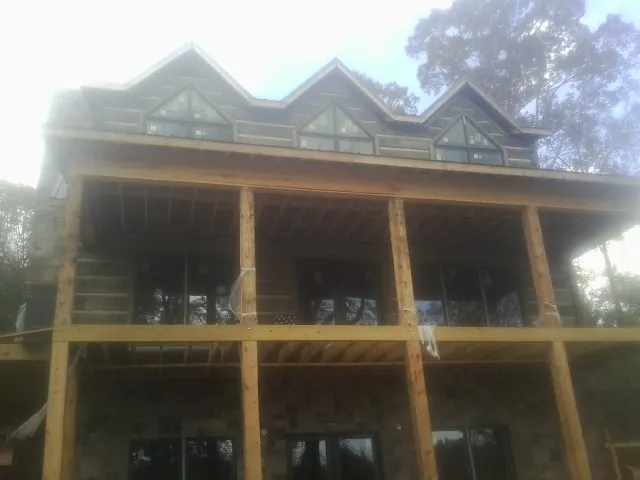 Dormers and porch framing on a large log home under construction — Roof Coating work by our crew in Cannonville