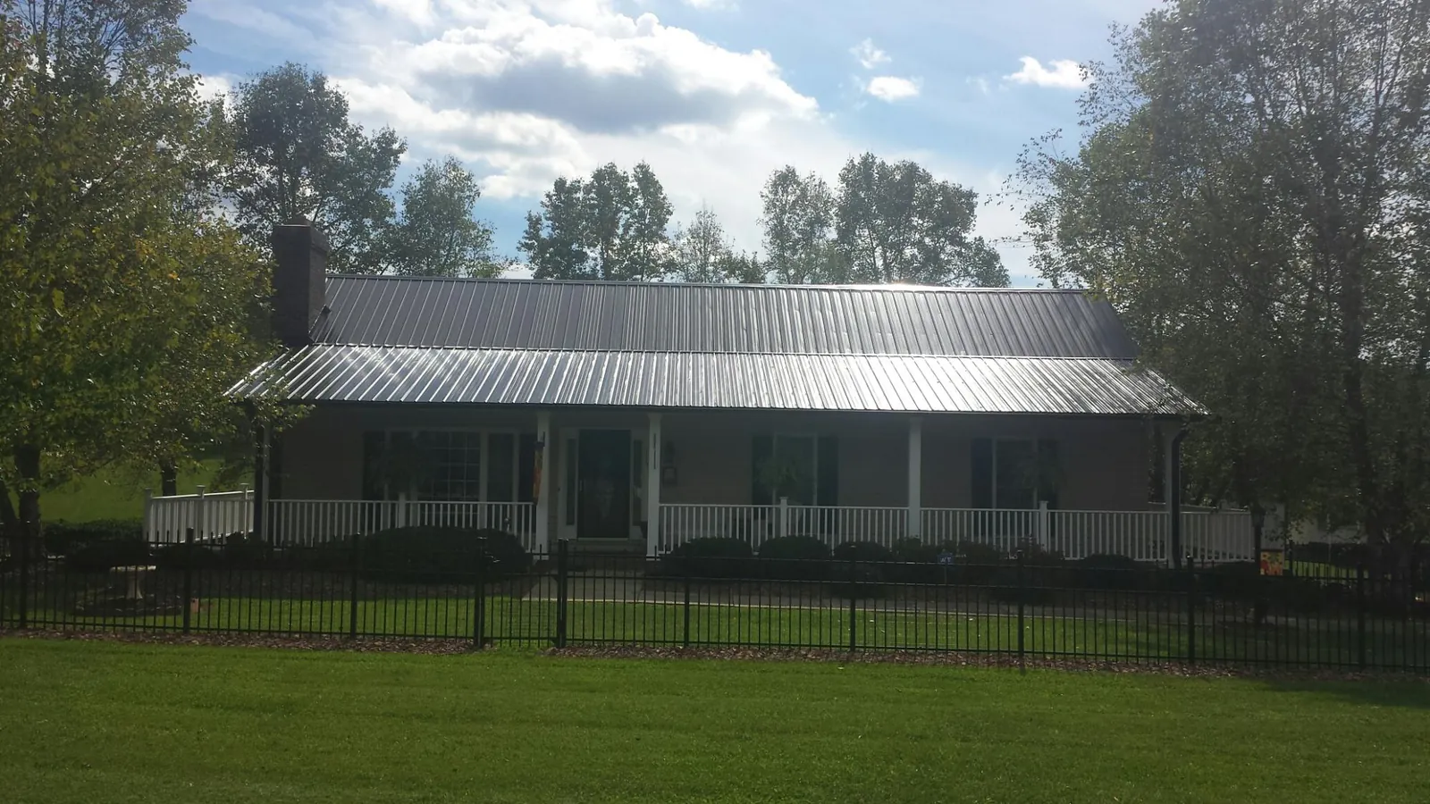 Gray metal roof on a brick ranch with a full width front porch — Gutter Guard Installation work by our crew in Cannonville