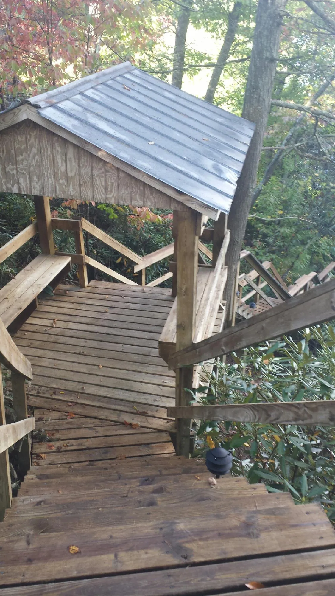 Metal roofed shelter over wooden steps on a wooded walkway — Skylight Repair & Installation work by our crew in Cannonville