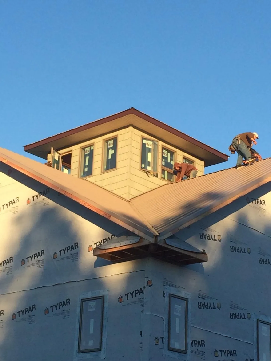 Roofers working around a rooftop cupola on a new metal roof at sunset — Roof Waterproofing in Cannonville by Roofing Brothers